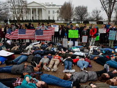 Belasan siswa SMA bersama dengan pengunjuk rasa berbaring di jalan depan Gedung Putih, Washington, Senin (19/2). Mereka memprotes mengenai peraturan pengendalian senjata di Amerika Serikat. (AP Photo/Evan Vucci)