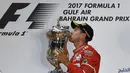 Sebastian Vettel mencium trofi juara yang diraihnya pada balapan F1 GP Bahrain di Sirkuit Sakhir, Manama, Minggu (16/4/2017).  (AFP/Andrej Isakovic)