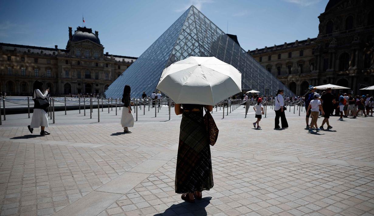 Seseorang berlindung di bawah payung di depan museum Louvre di Paris saat gelombang panas yang memecahkan rekor melanda sebagian besar Eropa Barat pada Kamis 28 Mei 2026. (SIMON WOHLFAHRT/AFP)