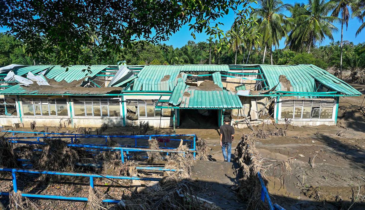 Sebulan lebih pasca terjangan banjir bandang, kondisi sejumlah Sekolah Dasar (SD) di Kabupaten Bireuen, Aceh, masih sangat memperihatinkan. Tampak dalam foto, seseorang berjalan menuju sekolah dasar yang hancur akibat banjir bandang di daerah yang berdekatan dengan Sungai Peusangan di Bireuen, provinsi Aceh, pada Senin 5 Januari 2026. (CHAIDEER MAHYUDDIN/AFP)