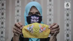Pekerja menunjukkan masker bermotif batik Betawi yang selesai dibuat di Butik Elemwe, Jakarta, Selasa (22/12/2020). Elemwe memiliki rancangan khas dalam membuat masker dengan menggunakan batik Betawi. (merdeka.com/Iqbal S. Nugroho)