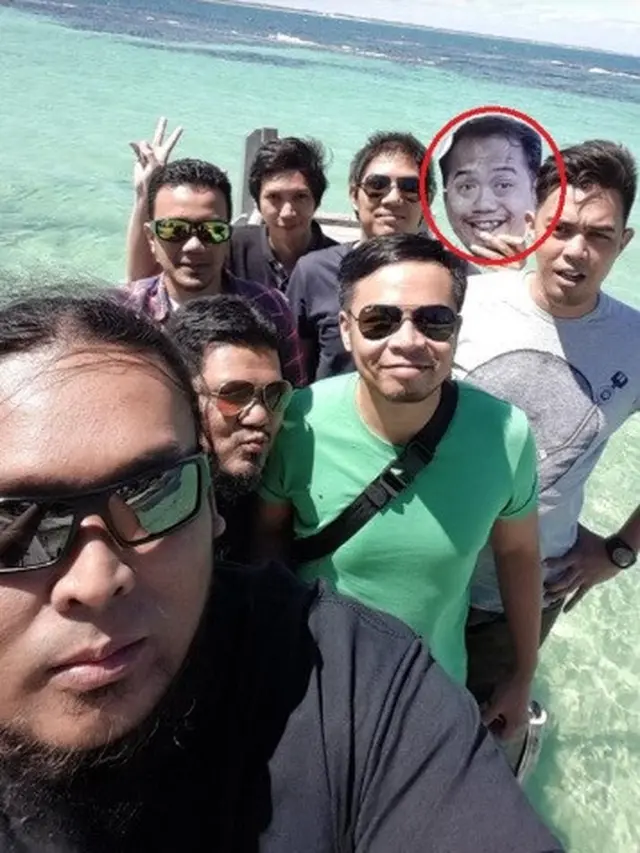 pria bawa foto sahabat ketika berlibur