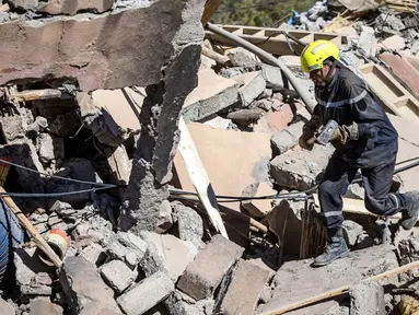 Seorang pekerja penyelamat mencari korban selamat pada reruntuhan rumah yang rusak akibat gempa di Talat-n-Ya'qoub, Provinsi Al-Haouz, Maroko, Senin (11/9/2023). Jumah korban tewas akibat gempa Maroko bertambah lagi menjadi 2.862 orang per Senin (11/9/2023) pukul 20.00 waktu setempat atau Selasa (12/9/2023) pukul 02.00 WIB. (Fadel SENNA/AFP)