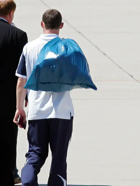 Penyerang Manchester United, Wayne Rooney berjalan membawa kantong kresek berisi barang-barang pribadinya menuju pesawat British Airways di bandara Baden Baden 2 Juli 2006. (AFP PHOTO / ADRIAN DENNIS)