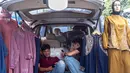 Langkah ini bertujuan untuk melindungi produsen lokal dan membantu industri tekstil bangkit dari krisis yang mengancam banyak pekerja dan menekan kinerja secara keseluruhan. Tampak dalam foto, pedagang menggunakan ponsel mereka sambil menunggu pelanggan di sebuah kios pakaian di salah satu pasar tradisional, Jakarta, Kamis 20 November 2025. (BAY ISMOYO/AFP)