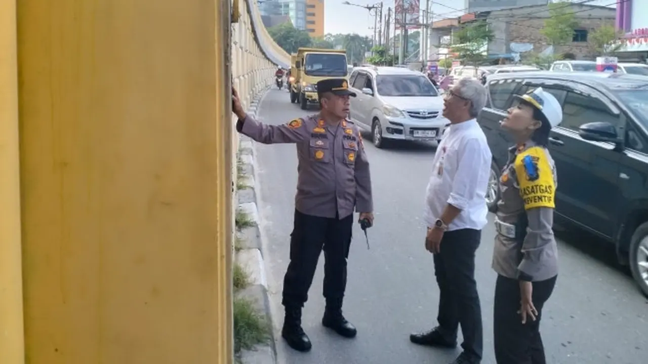Personel Polresta Pekanbaru dan pejabat dari Pemerintah Provinsi Riau mengecek jembatan retak di Pekanbaru.