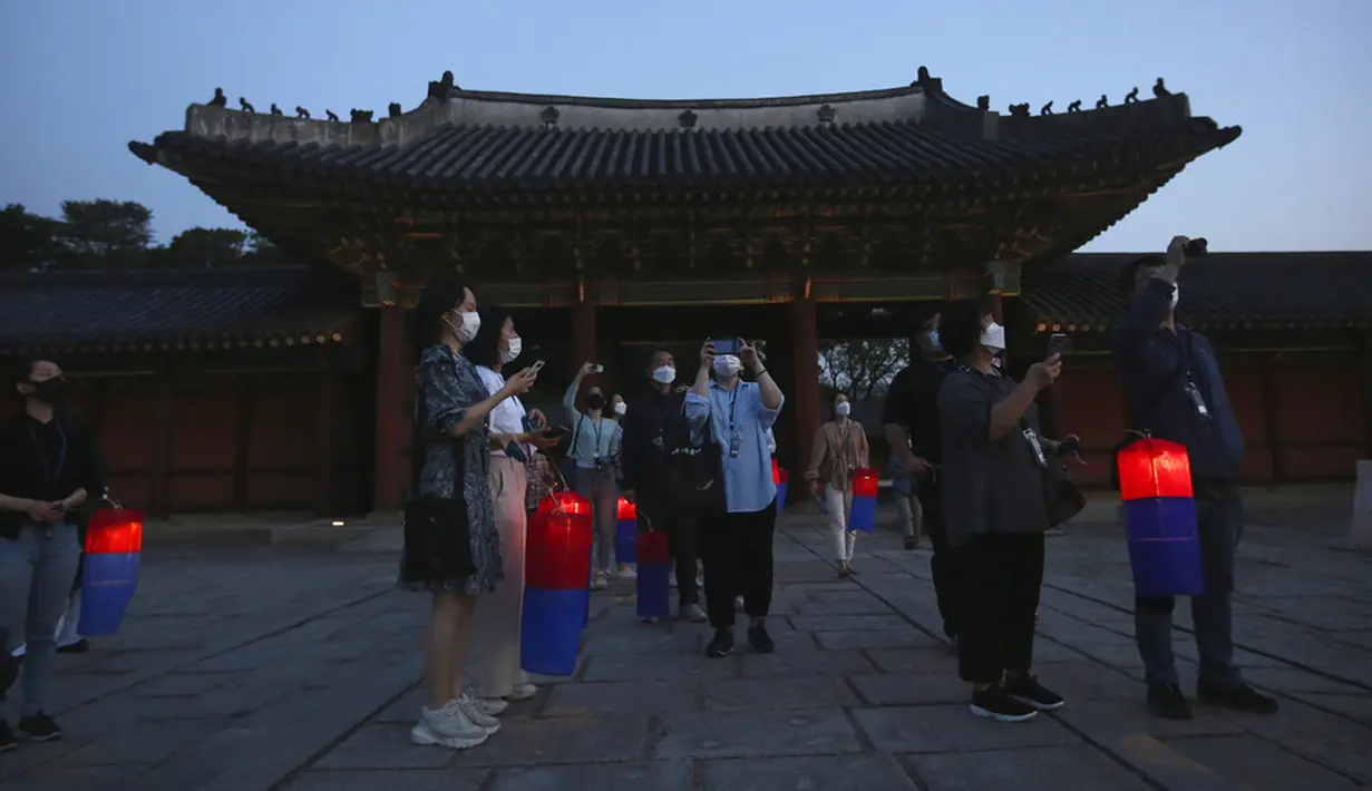 Pengunjung yang memegang lentera tradisional Korea berfoto selama Tur Cahaya Bulan di tengah pandemi virus corona COVID-19 di Istana Changdeokgung, Seoul, Korea Selatan, Kamis (13/5/2021). Istana Changdeok adalah istana Dinasti Joseon. (AP Photo/Ahn Young-joon)