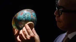 Wakil Ketua Sotheby's Asia, Nicolas Chow memegang mangkuk Dinasti Qing saat dipamerkan di Rumah Lelang Sotheby's di Hong Kong, Kamis (2/3). Diperkirakan, mangkuk ini akan terjual seharga USD 25,6 juta atau sekitar Rp 348 miliar. (ANTHONY WALLACE/AFP)