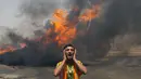 Petugas pemadam kebakaran Palestina berteriak saat berusaha memadamkan api yang berkobar di salah satu gudang di barat kota Gaza, (12/7/2014). (AFP PHOTO/Mahmud Hams)