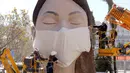 Pekerja memasang masker di salah satu patung raksasa yang akan ditampilkan di festival Las Fallas atau festival api di Valencia, Spanyol, Rabu (11/3/2020). Festival Fallas yang akan berlangsung pada 13 Maret telah dibatalkan karena wabah coronavirus. (AP Photo/Alberto Saiz)