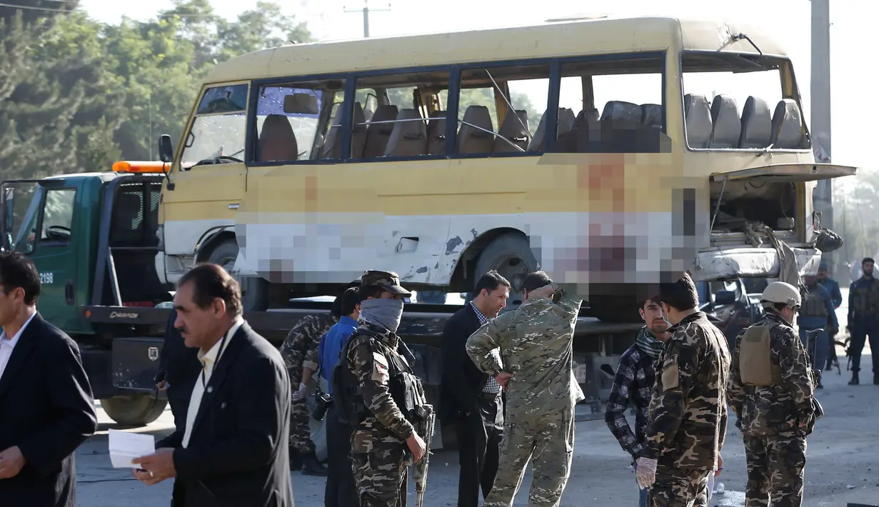 Petugas keamanan berjaga didekat minibus yang terkena serangan bunuh diri di Kabul, Afghanistan, Senin (20/6). Sebanyak 14 orang tewas akibat serangan ini. (REUTERS / Omar Sobhani)