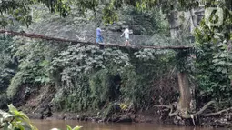 Anak-anak melintasi jembatan gantung yang sudah tidak layak di kawasan Srengseng Sawah, Jakarta, Sabtu (12/6/2021). Kondisi jembatan gantung yang menjadi akses warga dari Cimanggis menuju Srengseng Sawah atau sebaliknya tersebut beralaskan bambu serta seng. (merdeka.com/Iqbal S. Nugroho)