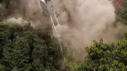 Momen saat peruntuhan sebuah jembatan gantung oleh para insinyur di Chirajara, Kolombia, Rabu (11/7). Sebelumnya, sebagian jembatan runtuh dan menewaskan sembilan pekerja saat pembangunannya pada Januari lalu. (AP Photo/Fernando Vergara)