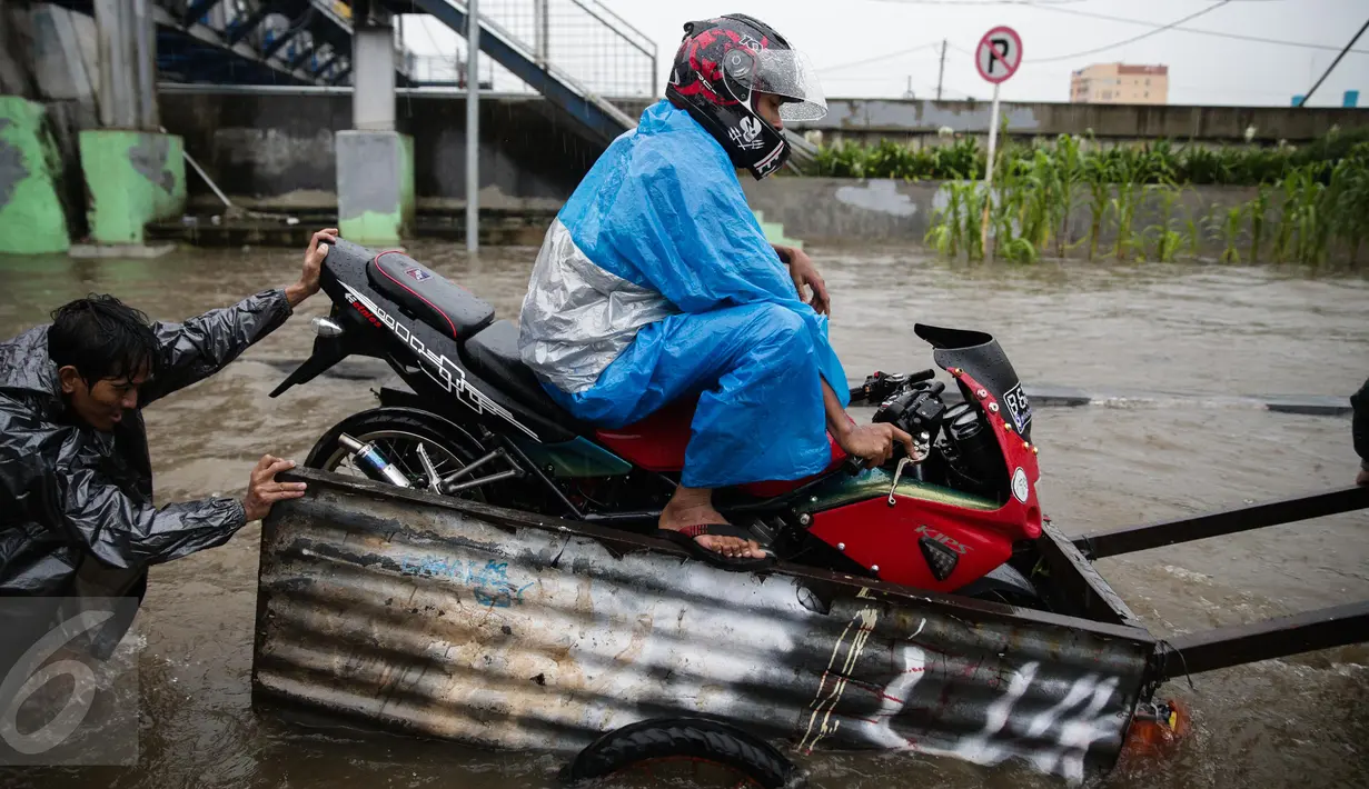 Pengendara sepeda motor memanfaatkan jasa gerobak untuk menyeberangi banjir di Jalan Gunung Sahari, Jakarta Pusat, Selasa (21/2). Hujan deras yang mengguyur sejak Selasa dini hari membuat sebagian wilayah di Jakarta banjir. (Liputan6.com/Faizal Fanani)
