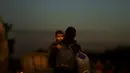 Seorang migran membawa anaknya setelah melintasi perbatasan Austria-Hungaria ke Nickelsdorf, Austria (21/9/2015). Diperkirakan sekitar 10.700 migran telah masuk ke Austria dari Hongaria pada hari Minggu (20/9) (REUTERS / David W Cerny)