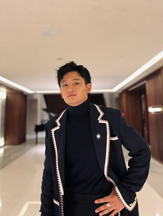 Ia memadukan blazer dengan turtleneck hitam, yang semakin memperkuat kesan maskulin dan eksklusif. Sepatu kulit hitam yang mengkilap menjadi pelengkap sempurna, memberikan aura gentleman yang kuat. [@lyodraofficial/@randymartinnn].