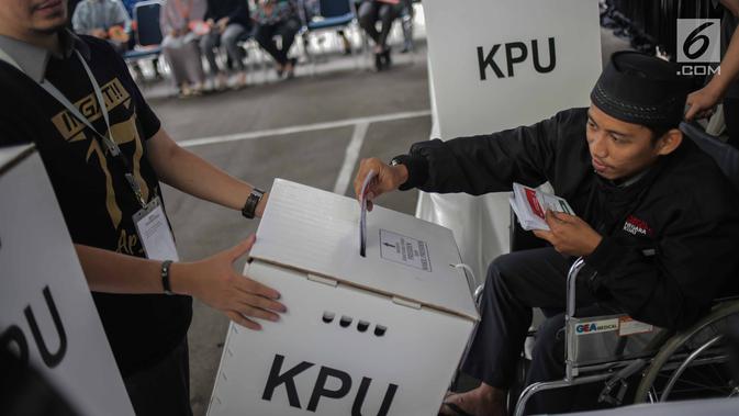 Penyandang disabilitas memasukkan surat suara ke dalam kotak saat simulasi pemungutan dan penghitungan suara Pemilu di halaman Gedung KPU, Jakarta, Selasa (12/3).  Simulasi untuk merepresentasikan pemungutan suara di TPS. (Liputan6.com/Faizal Fanani)