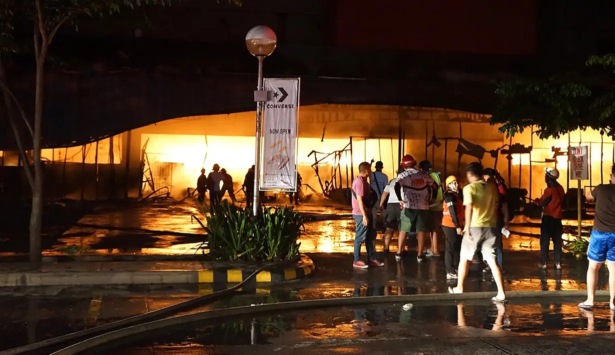 Petugas pemadam kebakaran mencoba memadamkan api di sebuah mal sesaat setelah gempa bumi bermagnitudo 6,4  melanda General Santos City, di pulau selatan Mindanao, Kamis (16/10/2019). Sekitar 100 anggota damkar dikerahkan untuk memadamkan api yang diduga akibat kebocoran gas. (EDWIN ESPEJO / AFP)