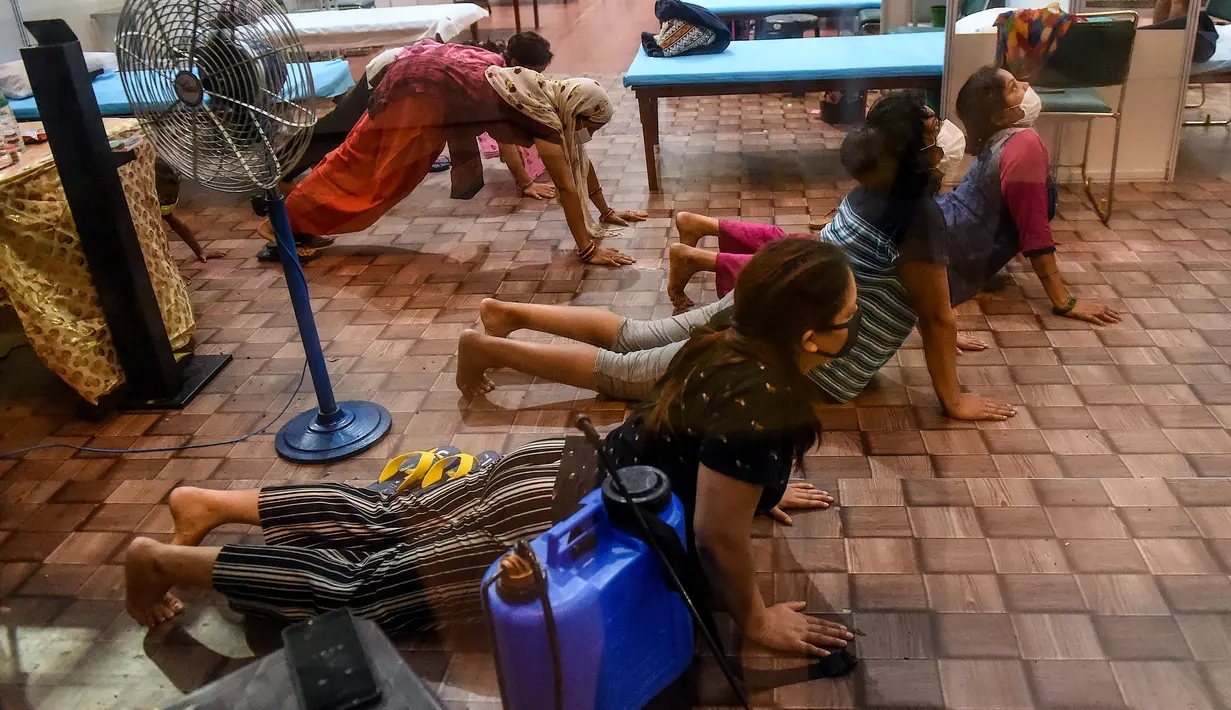 Pasien melakukan yoga di dalam bangsal di kompleks olahraga Commonwealth Games (CWG) Village yang sementara diubah menjadi pusat perawatan Covid-19 di New Delhi, India, Kamis (16/7/2020). Kasus virus corona (Covid-19) di India hampir menyentuh angka 1 juta orang.  (Money SHARMA / AFP)