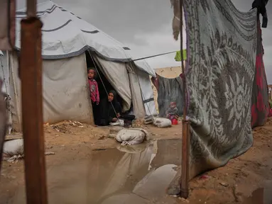 Nanaa Abu Jari memasak di luar tendanya setelah tenda tersebut terendam air hujan di Nuseirat, Jalur Gaza tengah, Jumat, 2 Januari 2026. Hingga awal Januari 2026, wilayah Gaza masih dihantam cuaca ekstrem yang memperparah krisis kemanusiaan di sana. (AP Photo/Abdel Kareem Hana)