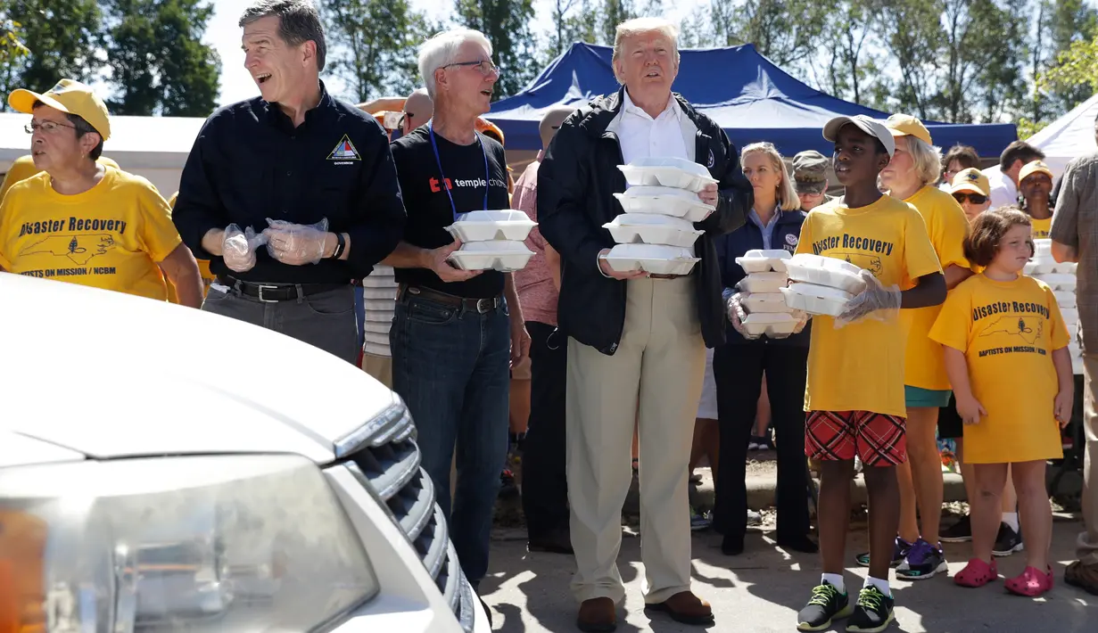 Presiden AS, Donald Trump membawa makanan sebelum dibagikan kepada korban badai Florence di Temple Baptist Church di New Bern, N.C. (19/9). Badai tersebut juga membuat hampir seluruh kota di North Carolina dibanjiri lumpur dan air. (AP Photo /Evan Vucci)