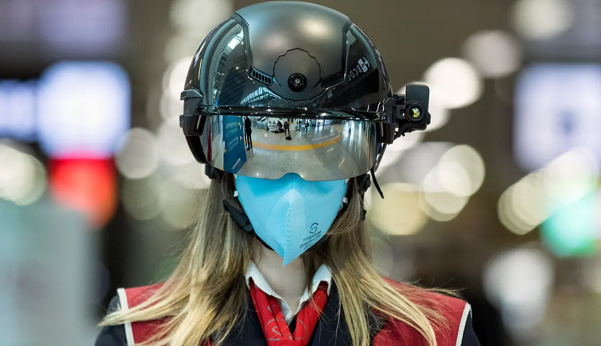Seorang petugas mengenakan pemindai 'helm pintar' untuk mengukur suhu tubuh penumpang di bandara internasional Leonardo da Vinci, Roma, Italia pada 6 Mei 2020. Hal ini dilakukan guna menyaring orang yang memiliki gejala infeksi virus corona. (Roberto Monaldo/LaPresse via AP)