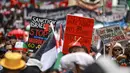 Angka ini jauh lebih tinggi dibanding laporan resmi otoritas kesehatan Gaza yang mencatat sekitar 49.000 kematian. Tampak dalam foto, para demonstran pro-Palestina membawa bendera, spanduk, dan plakat saat mereka berbaris berunjuk rasa di jalanan kota Sydney, Australia, Minggu 22 Februari 2026. (DAVID GRAY/AFP)