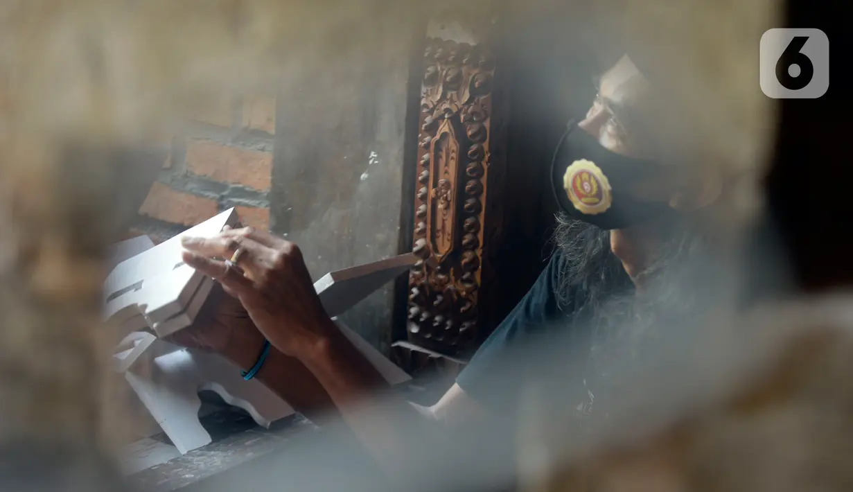 Perajin, Seno (47), menyelesaikan lukisan rekal atau tatakan Al Quran untuk anak-anak di Perumahan Gading Depok, Curug, Bojongsari, Depok, Jumat (25/09/2020). Di masa pandemi, tatakan Al Quran dan talenan lukis yang dijual seharga Rp 50 ribu mengalami penurunan pemesanan. (merdeka.com/Dwi Narwoko)