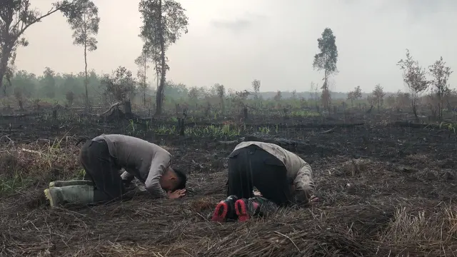 Anggota polisi Satgas Karhutla sujud syukur hujan turun.