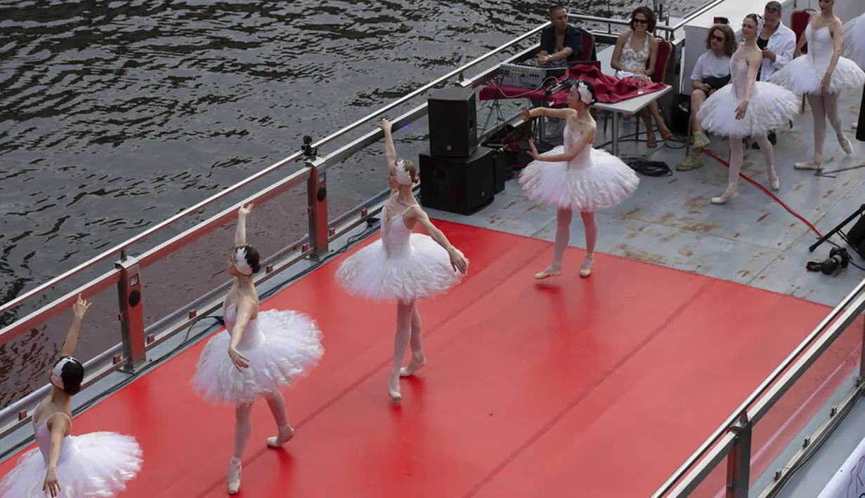 Anggota Staatsballett Berlin menari di atas kapal pesiar selama tur melalui pusat kota di Berlin, Jerman, Kamis (10/6/2021). Pertunjukan itu diikuti oleh banyak orang di sepanjang rute. (Paul Zinken/dpa via AP)