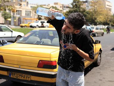 Seorang sopir taksi Iran mendinginkan diri dengan menyiramkan air ke wajahnya di sebuah jalan di tengah suhu yang melonjak di Teheran pada 22 Juli 2025. (Foto oleh AFP)