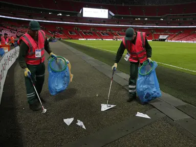 Petugas mengumpulkan pesawat terbang kertas yang dilemparkan suporter selama pertandingan Inggris melawan Slovenia di kualifikasi Piala Dunia 2018 di stadion Wembley, London, (5/10). AFP Photo/Adrian Dennis)