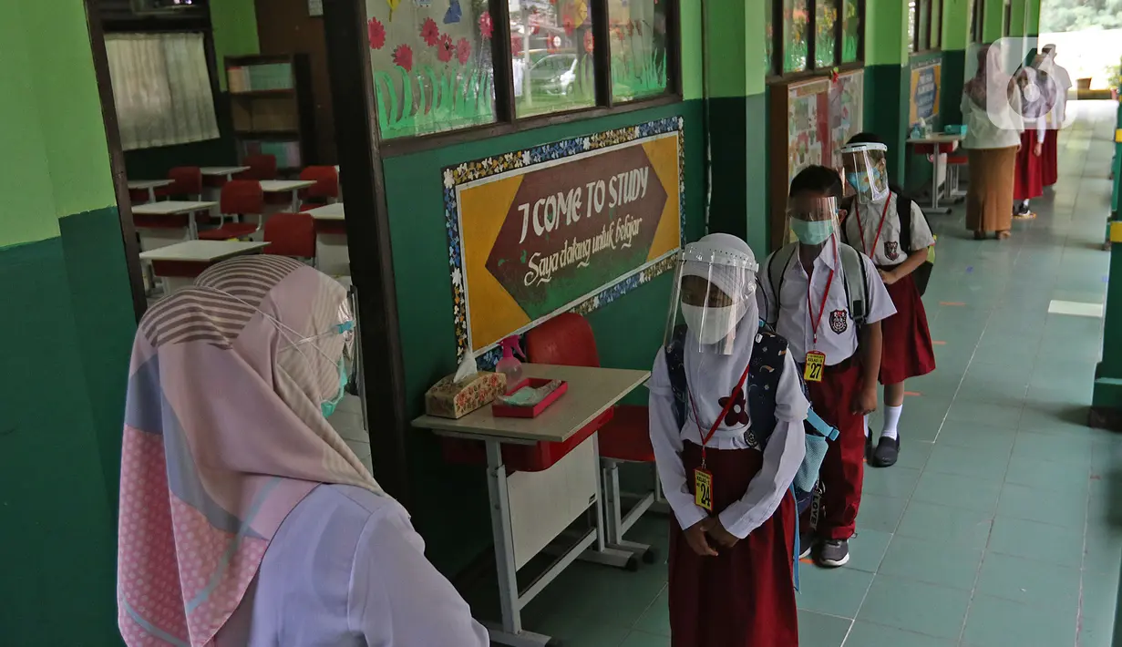 Sejumlah murid menerapkan jaga jarak sebelum masuk ke sekolah di SD Negeri 6, Bekasi, Jawa Barat, Selasa (4/8/2020). Pemerintah setempat memberikan izin kepada enam sekolah untuk melakukan uji coba pembelajaran tatap muka selama satu bulan. (Liputan6.com/Herman Zakharia)