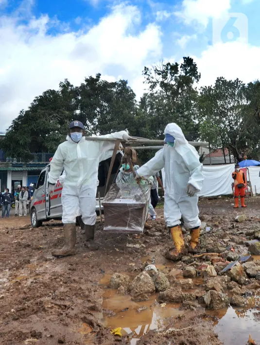 Petugas yang mengenakan APD membawa peti berisi jenazah dengan protokol COVID-19 di TPU Srengseng Sawah 2, Jakarta, Selasa (9/2/2021). Sudah lebih dari sepekan TPU Srengseng Sawah 2 menerima pemakaman korban COVID-19 dengan jumlah yang dimakamkan sehari maksimal 10 jenazah. (merdeka.com/Arie Basuki)