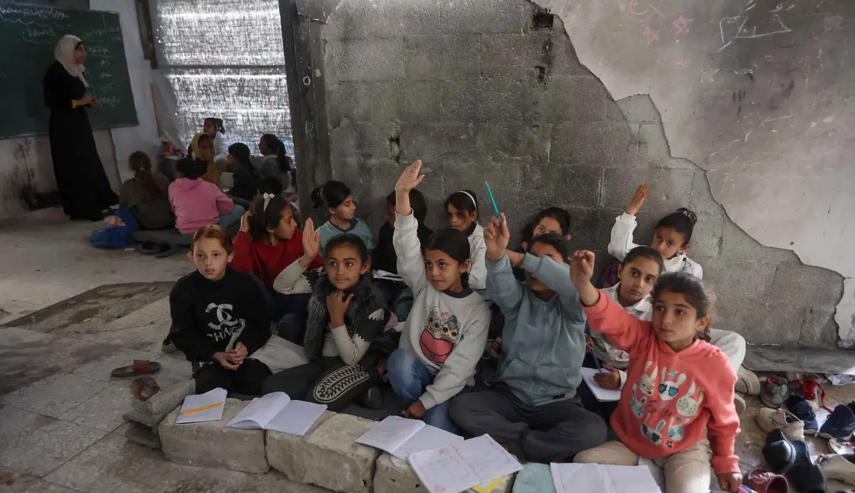 Berdasarkan laporan dari UNRWA per Februari 2026, hampir 90 persen bangunan sekolah di seluruh Jalur Gaza telah rusak atau hancur. Tampak dalam foto, anak-anak pengungsi Palestina mengikuti belajar mengajar di dalam tenda di Sekolah Mada, kamp pengungsi Jabalia, Jalur Gaza Utara pada 13 April 2026. (Omar AL-QATTAA/AFP)
