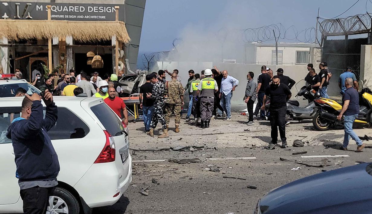 Petugas pertolongan pertama dan warga yang lewat berkumpul di sekitar reruntuhan kendaraan yang menjadi sasaran serangan pesawat tak berawak Israel di kota Jiyeh, Selatan Beirut, pada Rabu 13 Mei 2026. (Fadel ITANI/AFP)