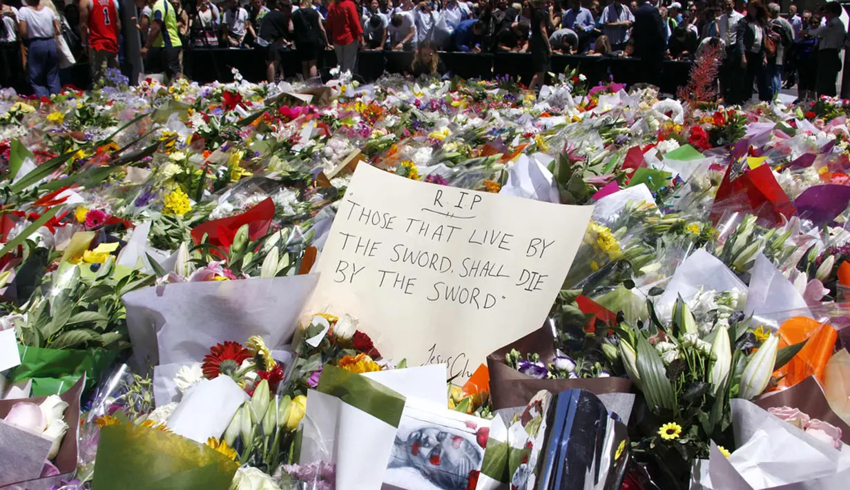Sejumlah orang berdiri di balik pembatas tumpukan bunga di dekat Kafe Lindt, Sidney, Australia (16/12/2014). (REUTERS/David Gray)