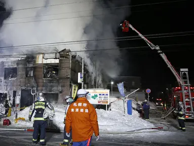 Petugas pemadam kebakaran berupaya memadamkan api yang melahap sebuah panti jompo di Sapporo, utara Jepang, Kamis (1/2). Sebanyak 11 orang tewas dan lima lainnya menderita luka dalam insiden kebaran tersebut. (Yuya Shino/Kyodo News via AP)