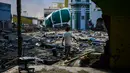 Warga melewati puing-puing dekat Masjid Raya Baiturrahman yang runtuh setelah gempa bumi dan tsunami di Palu, Sulawesi Tengah, Rabu (3/10). Meski kubah dan beberapa dinding masjid runtuh, namun menaranya masih kokoh berdiri. (AFP PHOTO / JEWEL SAMAD)