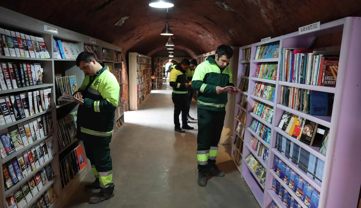 Petugas kebersihan membaca buku di perpustakan tempat mereka bekerja di distrik Cankaya, Ankara, Turki (9/1).Beberapa petugas ini membuat band bernama "Grup Tin", dengan menggunakan tempat sampah dan barang bekas sebagai alat musik. (AFP Photo/Adem Altan)