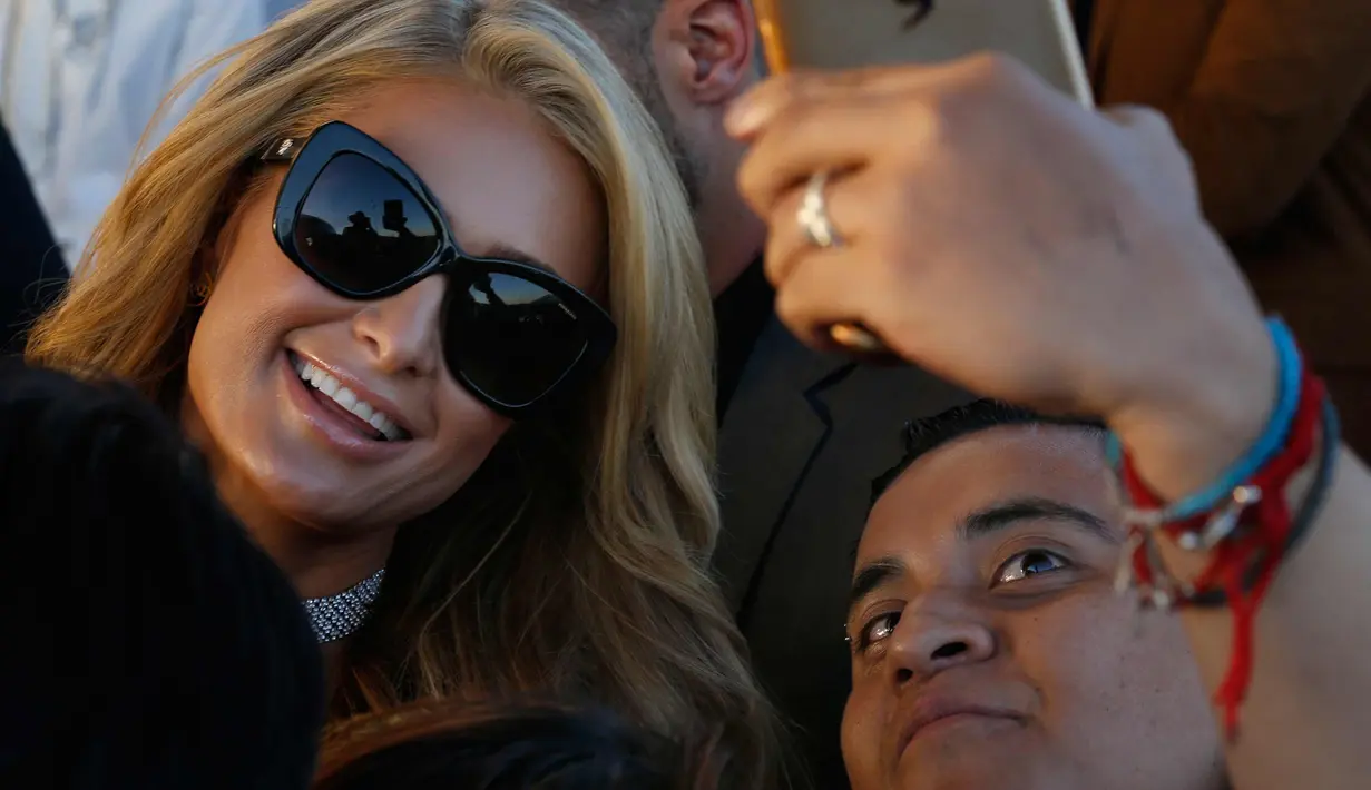 Aktris Paris Hilton berselfie dengan fansnya saat tiba di Arco Norte Store di Mexico City, (8/11). Kehadiran Paris Hilton di Meksiko untuk mempromosikan sepatu terbarunya. (AP Photo / Marco Ugarte)