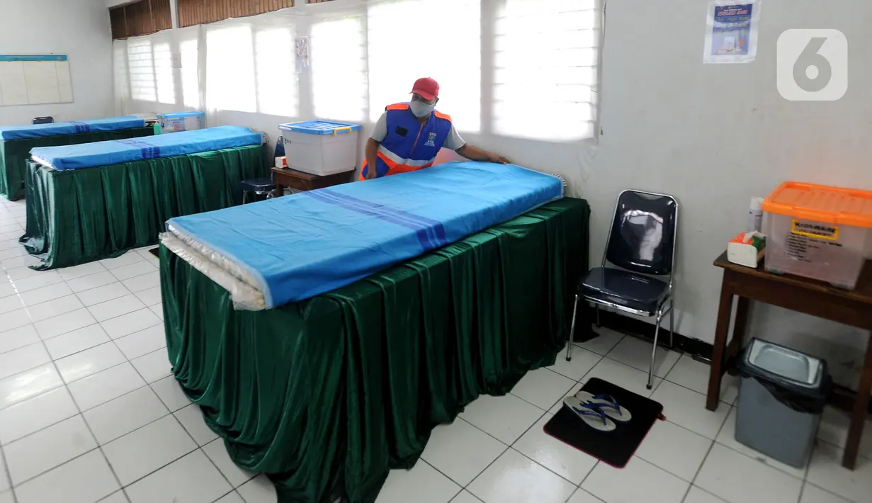 Petugas gugus tugas Covid-19 RW 03 merapikan tempat tidur untuk isolasi mandiri di Gedung Sasana Krida Karang Taruna, Kelurahan Pondok Labu, Jakarta, Selasa (19/1/2020). Penyediaan kamar isolasi ini sebagai antisipasi apabila tempat isolasi mandiri yang disediakan pemerintah penuh. (merdeka.com/Arie