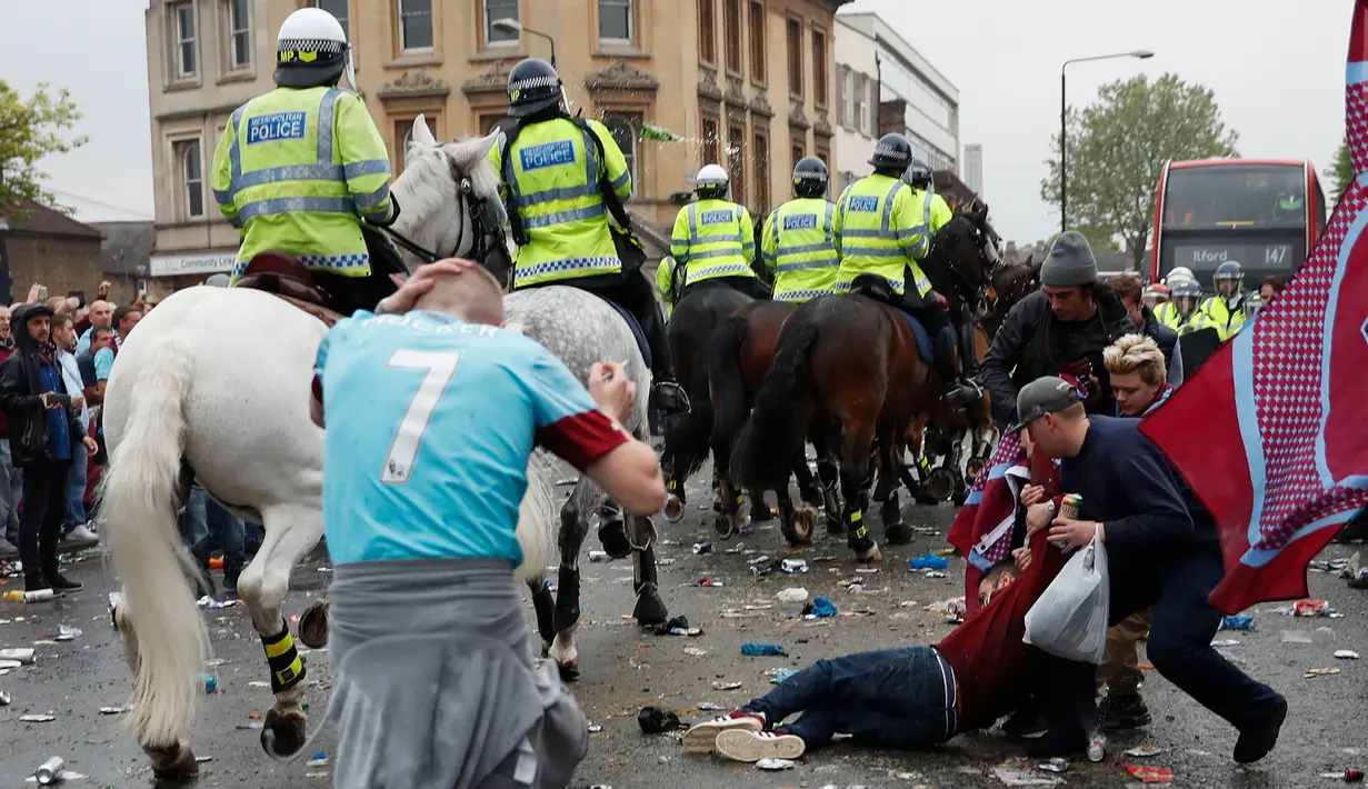 Suporter West Ham United tergeletak di jalanan saat bentrok dengan petugas kepolisian di depan Stadion Boleyn Ground, London, Selasa (10/5). Bentrokan terjadi akibat suporter West Ham United menyerangan bus skuat Manchester United. (Reuters/Eddie Keogh)