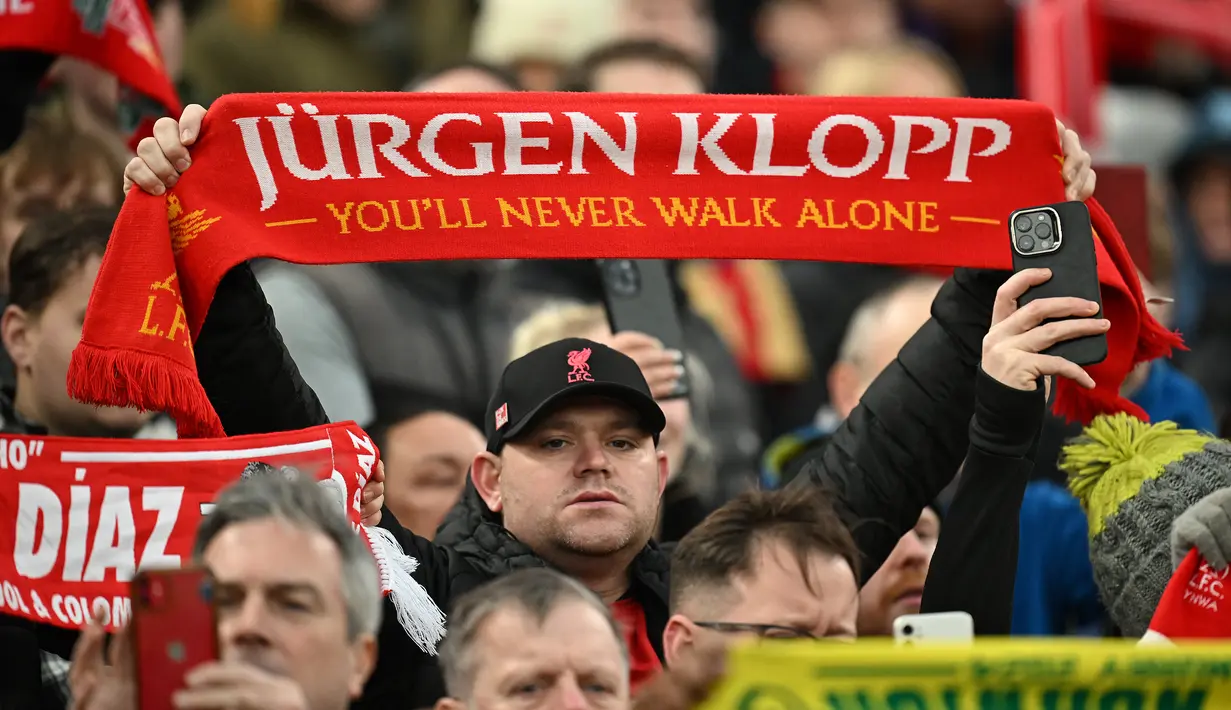 Seorang fans Liverpool membentangkan syal yang bertuliskan "Jurgen Klopp, kamu tak akan berjalan sendirian" saat laga putaran keempat Piala FA melawan Norwich City di Anfield, Liverpool, Inggris, Minggu (28/01/2024). (AFP/Paul Ellis)