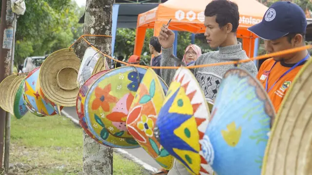 Tim juri lomba melukis caping menilai karya peserta yang dipajang di tepi sungai irigasi Kelurahan Toyareja, Kecamatan Purbalingga, Sabtu (11/1/2020). (Foto: Liputan6.com/Rudal Afgani)