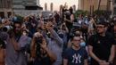Orang-orang mengambil gambar saat matahari terbenam di Manhattan ketika fenomena "Manhattanhenge" di 42nd street, New York, Senin (11/7/2022). Dikenal dengan sebutan Manhattanhenge, fenomena terbenamnya matahari yang satu ini selalu membuat jalanan Manhattan macet. (Yuki IWAMURA / AFP)