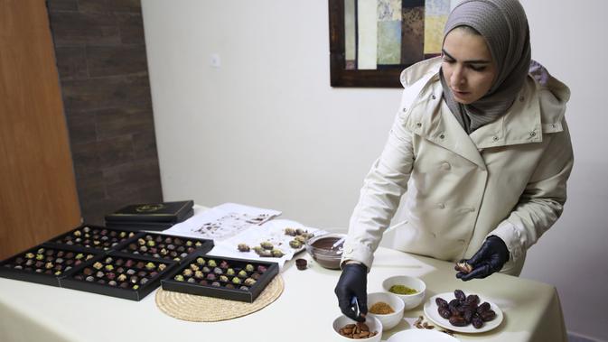 Wanita Palestina bernama Sojood Silwadi membuat kurma berlapis cokelat di rumahnya di Kota Nablus, Tepi Barat, 15 November 2020. Dia menemukan cara mendapatkan sumber penghasilan stabil dengan membuat kurma cokelat isi kacang dan menjualnya kepada pelanggan via media sosial. (Xinhua/Ayman Nobani)