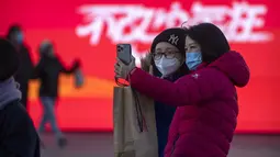 Pengunjung yang mengenakan masker berfoto selfie di pusat perbelanjaan kelas atas pada hari terakhir pekan liburan Tahun Baru Imlek di Beijing, Jumat, 27 Januari 2023. (AP Photo/Mark Schiefelbein)