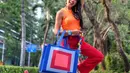 Nirina Zubir tampil awet muda dengan outfit colorfulnya. Ia mengenakan tank top oranye, dipadu celana panjang merah, memamerkan tote bagnya yang bernuansa biru dengan paduan warna biru muda, merah, dan pink, dipadunya dengan sneakers senada. [Foto: Instagram/nirinazubir]