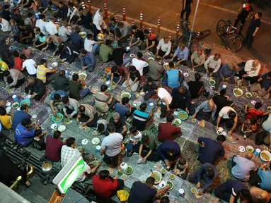 Warga muslim Iran menikmati menu makanan berbuka puasa di sebuah jalan di Teheran, 29 Mei 2018. Mereka yang sedang berpuasa dan berada jauh dari tempat tinggalnya mengikuti tradisi buka bersama di jalanan. (AP Photo/Vahid Salemi)